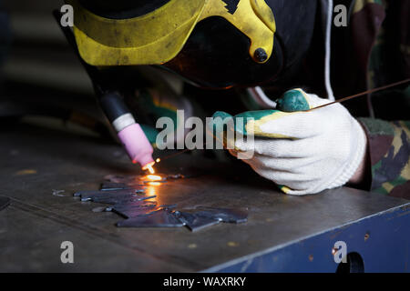 Professional woman worker welding metal parts with electric torch in workshop.Rare female occupation in heavy industry.Specialized welder tools in use Stock Photo