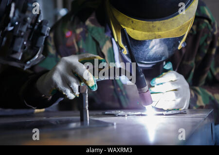 Professional woman welder works in workshop.Electric welding machine in use.Heavy industry worker working in shop.Metal products manufacturing at fact Stock Photo