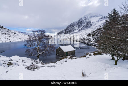 Llyn Ogwen in winter looking east showing boathouse with the A5 road and Tryfan mountain on right Snowdonia National Park North Wales UK February 2018 Stock Photo