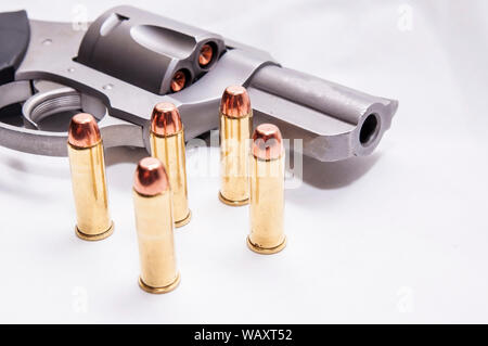A stainless, snub nosed  357 magnum revolver with five full metal jacket bullets next to it on a white background Stock Photo