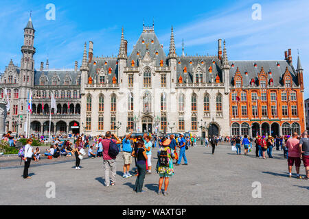 The Market Square with the neo-Gothic Province Court building, crowded with sightseeing tourists on a sunny afternoon in summer. Bruges, Belgium. Stock Photo