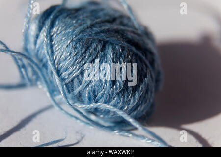 a light blue yarn seam with cotton thread on light simple background at Umedalen Stock Photo