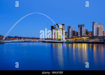 Early evening blue hour skyline view of lights and reflection of modern buildings and Millennium Bridge in Gateshead viewed across the river Tyne