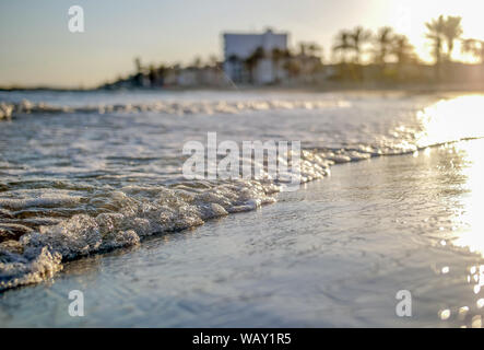 Beautiful waves wash the beach at sunset, blurred horizon Stock Photo