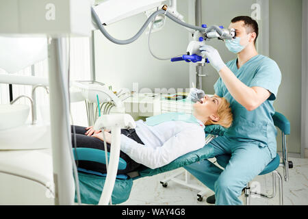 Male dentist looking through a microscope Stock Photo