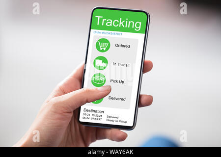 Customer Checking Shipment Tracking On Website On Smartphone Over White Desk Stock Photo