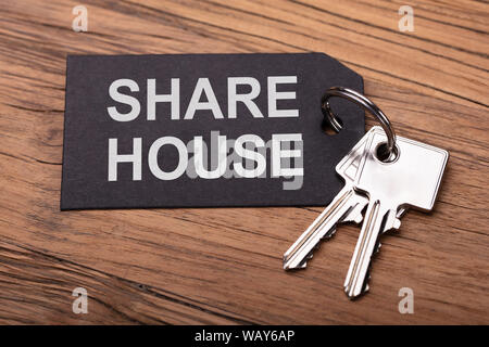 Share House Keys With Black Keychain On Wooden Desk Stock Photo