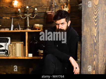 Spending great time at home. Man with beard looks strictly. Man bearded enjoy evening, wooden background. Guy in cozy warm atmosphere relaxing but Stock Photo
