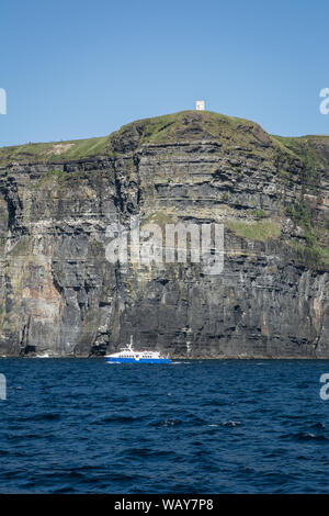 Tour boat on an evening cruise along the Cliffs of Moher on Ireland's atlantic west coast in County Clare Stock Photo