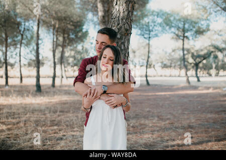 boyfriend hugs girlfriend from behind with eyes closed Stock Photo