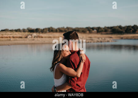 woman hugs man in a lake at sunset Stock Photo