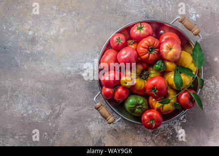 Ripe tomatoes in a pan on stone background, copy space. Stock Photo