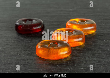 Group of four whole orange and dark red colourful hard candy on grey stone Stock Photo