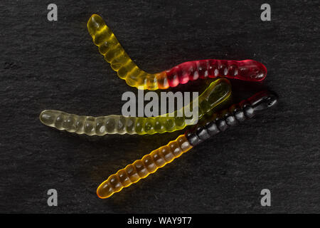 Group of three whole colourful jelly worm candy flatlay on grey stone Stock Photo