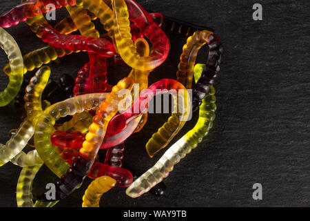 Lot of whole bright colourful jelly worm candy flatlay on grey stone Stock Photo