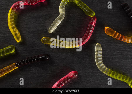 Lot of whole colourful jelly worm candy flatlay on grey stone Stock Photo