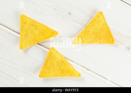 Group of three whole cheese tortilla chips flatlay on white wood Stock Photo