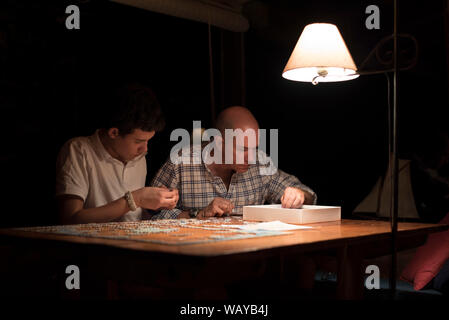 Father and Son Doing Jigsaw Puzzle at Night Stock Photo