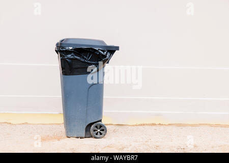 Gray garbage container with garbage bag isolated on light background, trash can. Stock Photo
