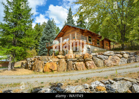 A picturesque rustic log home in the mountains surrounded by pine trees on a rocky hillside in Coeur d'Alene, Idaho. Stock Photo