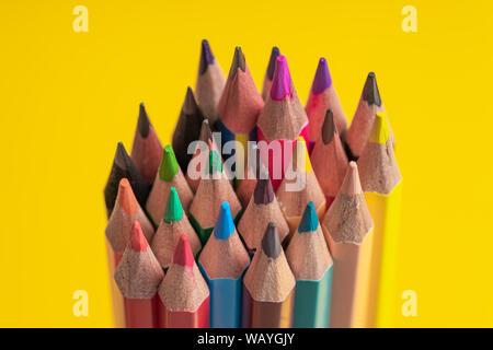 Many sharpened colored pencils laid out on a yellow background. Copyspace Stock Photo