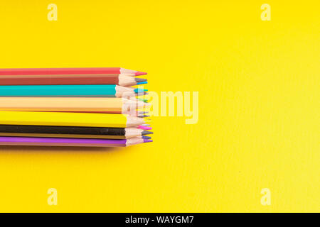 Many sharpened colored pencils laid out on a yellow background. Copyspace Stock Photo