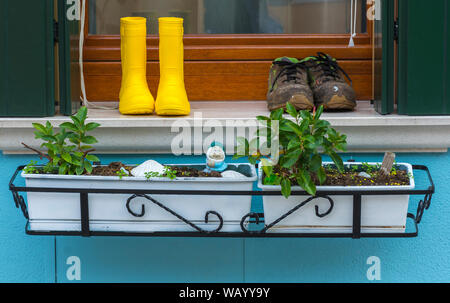 Boots and a window box on a building on the Calle ll dei Squeri, Burano, Laguna Veneto, Italy Stock Photo