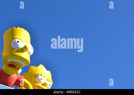 Slight closeup shot of Bart and Lisa Simpsons statues under a blue sky Stock Photo