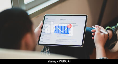 Young businessman checking his email on tablet in comfortable workplace Stock Photo
