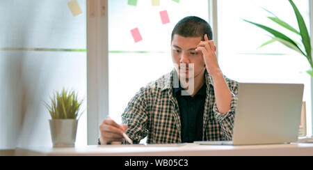 Young male designer working on his project and looking stressful in modern office room Stock Photo
