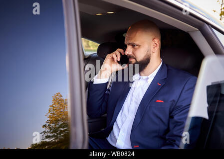 Successful young man talking on the phone in a car. Stock Photo