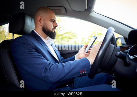 Successful young man with a phone in a car. Stock Photo