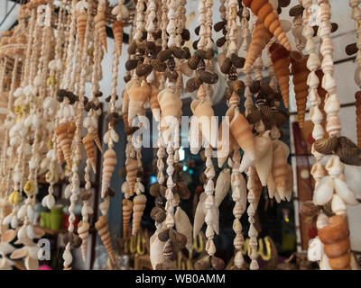 Traditional colorful home decorations made from different shape and color seashells. Souvenir hangings on the tropical sea resort market Stock Photo