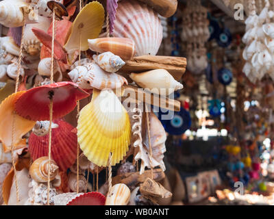 Traditional colorful home decorations made from different shape and color seashells. Souvenir hangings on the tropical sea resort market Stock Photo