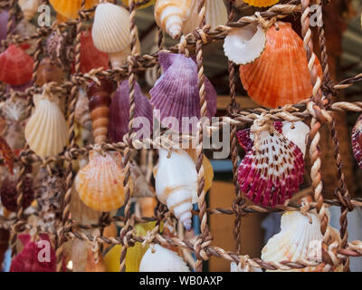 Traditional colorful home decorations made from different shape and color seashells. Souvenir hangings on the tropical sea resort market Stock Photo