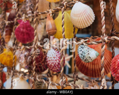 Traditional colorful home decorations made from different shape and color seashells. Souvenir hangings on the tropical sea resort market Stock Photo