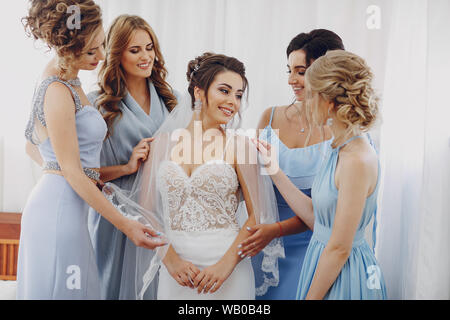 elegant and stylish bride along with her four girlfriends in blue dresses standing in a room Stock Photo