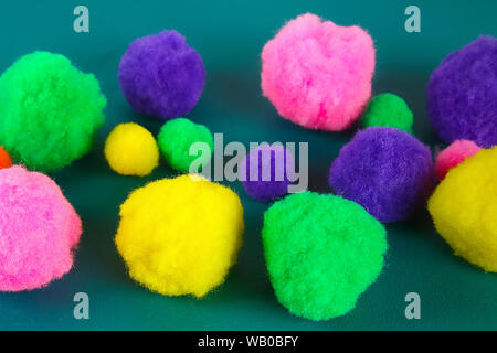 Colored beautiful pompons on a teal background. Assortment of pompons. DIY craft. Stock Photo