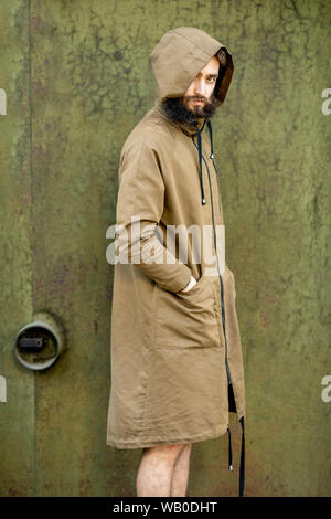 Portrait of a mysterious and weird man wearing hoodie coat on the green rusty wall background Stock Photo