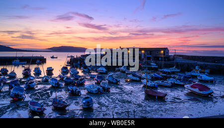 Lyme Regis, Dorset, UK. 23rd August 2019. UK Weather: Dawn colour at the historic Cobb Harbour at the coastal resort town of Lyme Regis.  Beautiful colours are reflected in the wet sand at low tide on what is forecast to be hot and sunny day at the start of the August Bank Holidy weekend. Credit: Celia McMahon/Alamy Live News. Stock Photo