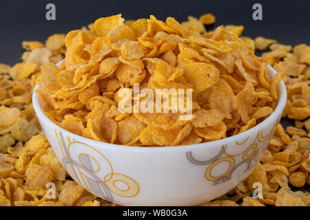 Cornflakes cereal in white blow, close-up isolated on black gray background, a delicious dietary breakfast. Selective Focus. Stock Photo