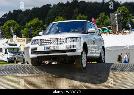 Range Rover Vogue (driver & passengers) driving on steep scary off-road display course - Land Rover Experience, Great Yorkshire Show, England, UK. Stock Photo