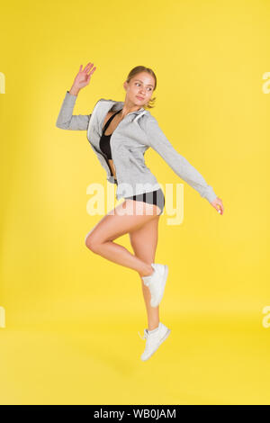 Young woman jumping in silhouette on yellow background. Dynamic movement. Side view. Stock Photo