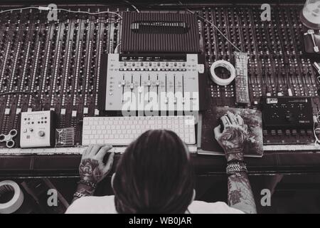 Overhead shot of a male working on mixing console and other recording studio equipment Stock Photo