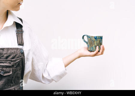 Woman with a blue ceramic mug in hand on a background of a white wall Stock Photo