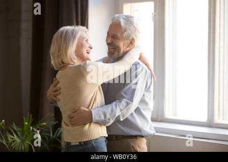 Happy old retired romantic couple dancing laughing in living room Stock Photo