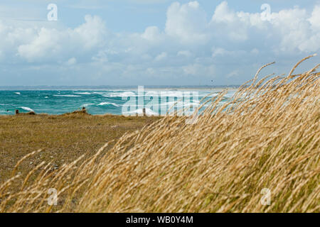 endless white sandy beach with dune grass and wooden fence in Brittany with Atlantic waves breaking on the shore Stock Photo