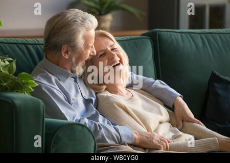 Happy senior old couple bonding embracing relaxing sit on sofa Stock Photo
