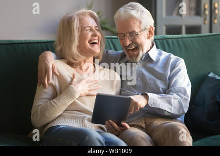 Cheerful old couple laughing using digital tablet at home Stock Photo