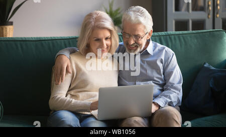 Happy old senior couple using laptop sit on sofa Stock Photo
